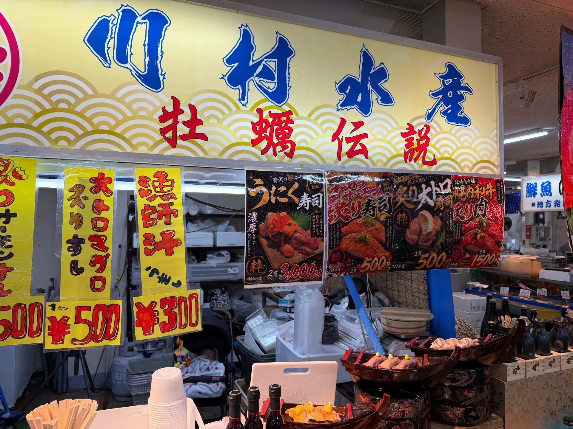 川村水産の店頭に掲げられた「牡蠣伝説」の看板とにぎり寿司のメニュー
