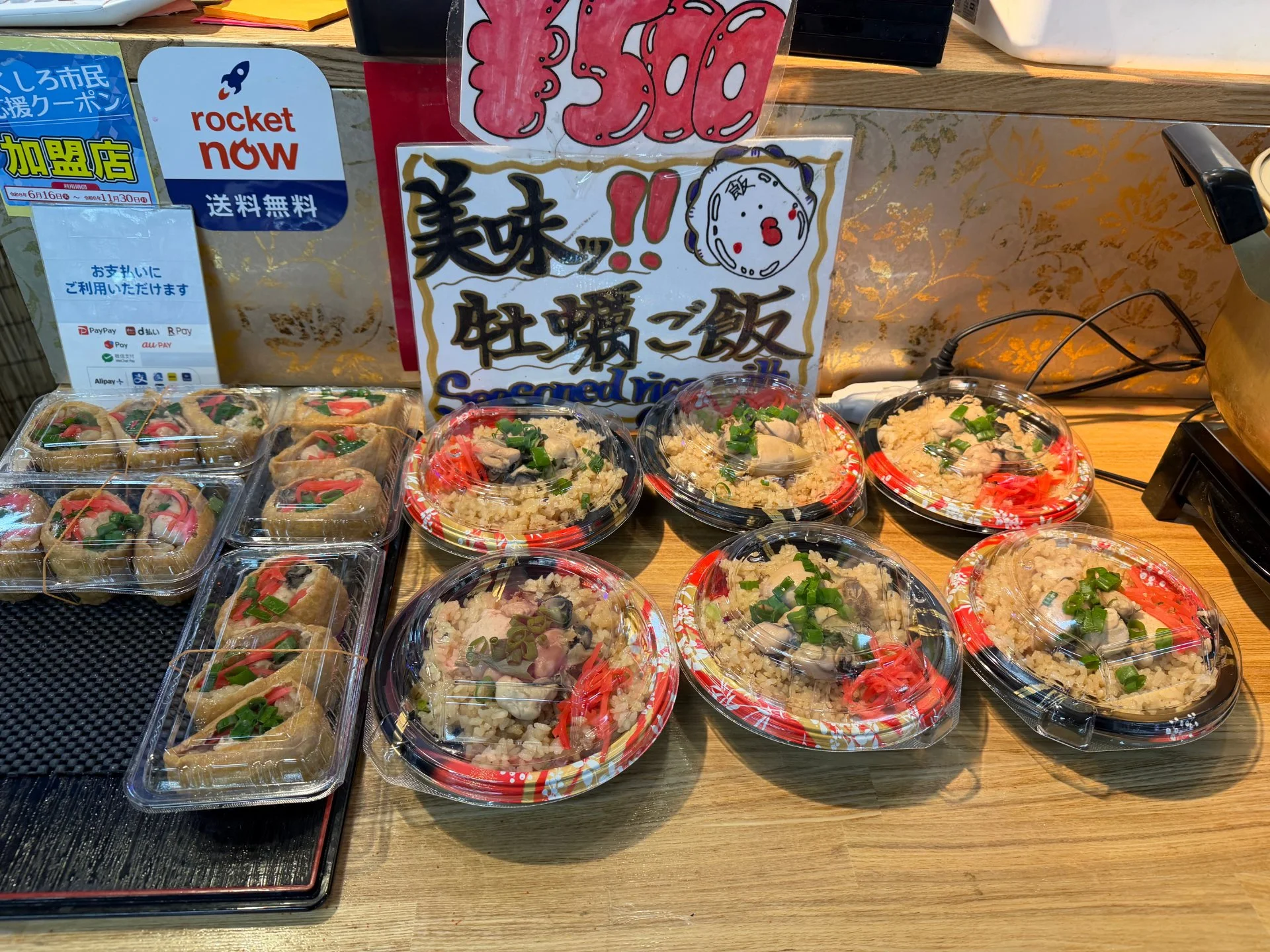 牡蠣ご飯の折詰と手作り稲荷寿司が並ぶ店頭の商品棚